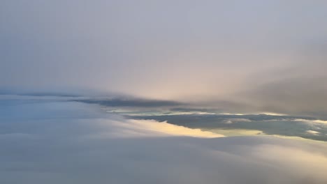 Flying-through-a-sky-plenty-of-colorful-fluffy-clouds-early-in-the-moring-in-a-real-time-flight,-shot-from-an-airplane-cabin-at-7000m-high-near-Barcelona,-Spain