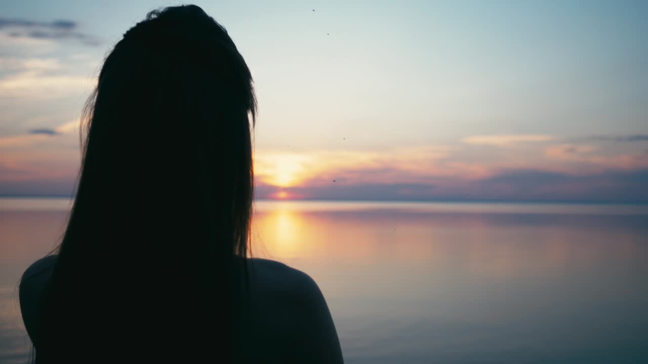 Beautiful Woman making heart shape with hands at sunset Girl holding up love symbol gesture with orange sun flare