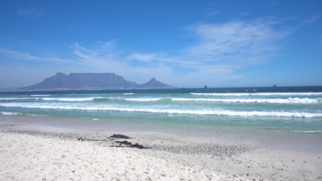 plano general de las olas del océano atlántico con la montaña de la mesa al fondo durante el buen tiempo