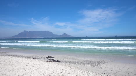 wideshot of atlantic ocean waves with the table mountain in the background during nice weather