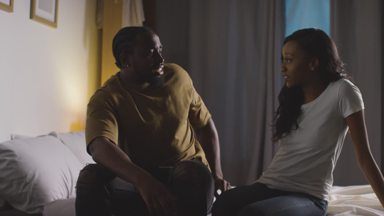 Couple At Home Sitting On Bed At Night Having Argument 7