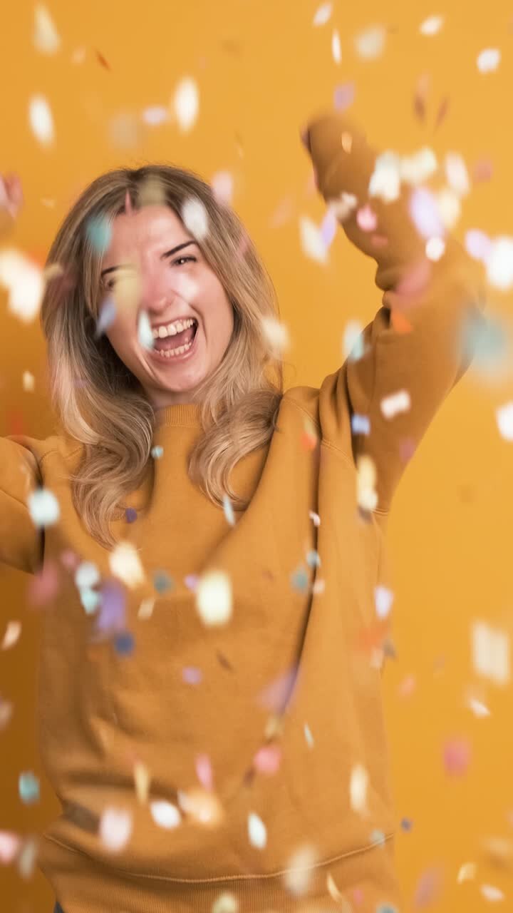 Donna eccitata con capelli biondi che esulta e festeggia un grande premio su sfondo giallo