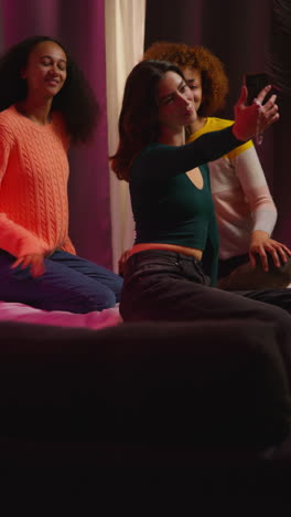 three young women taking a selfie on a bed at night