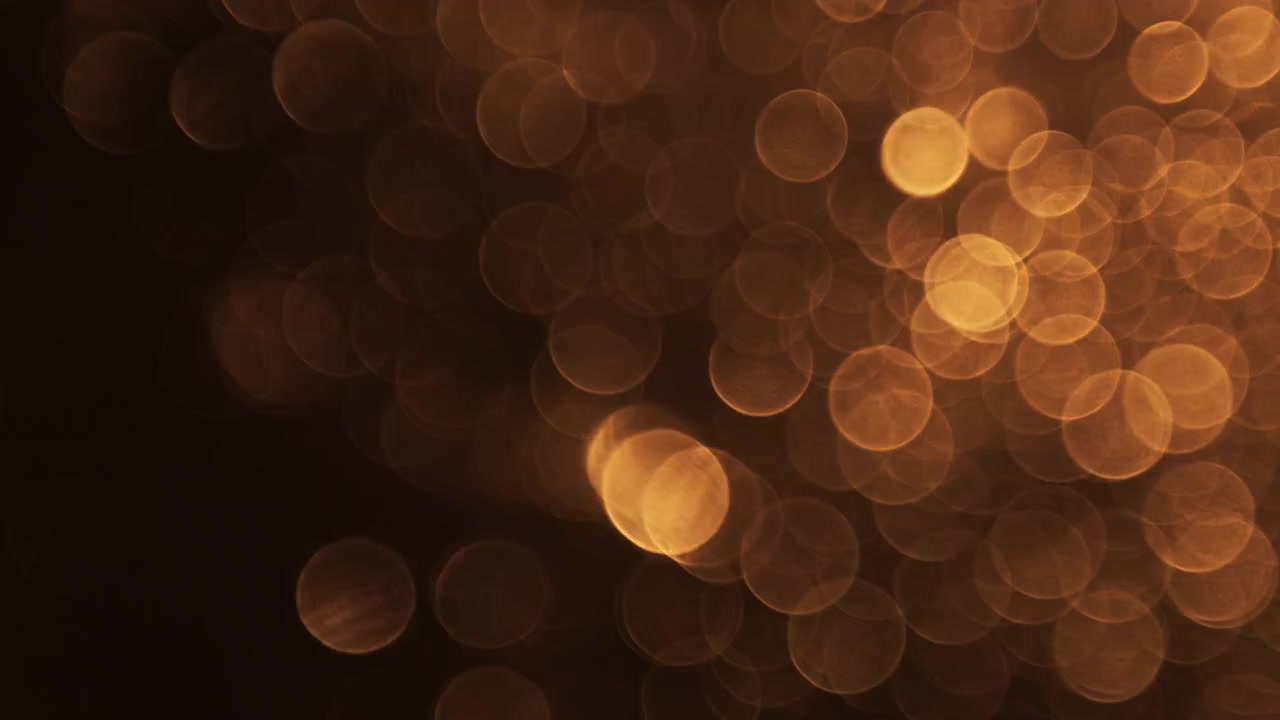 Luci bokeh dorate astratte che sfumano su sfondo nero