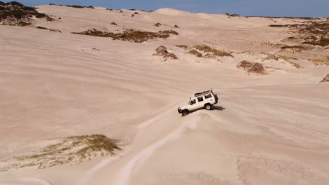 aerial of safari jeep vehicle driving across the sand dunes