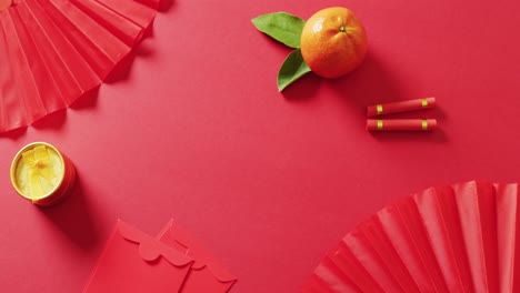 Video-of-envelopes,-oranges-and-fans-on-red-background