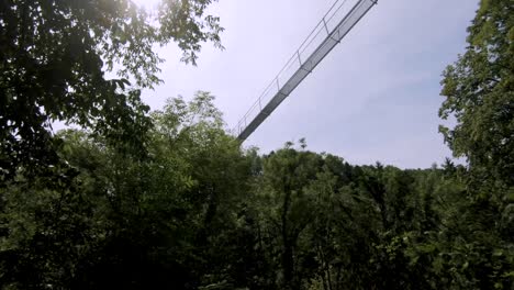 moving shot of a suspension bridge over a forested gorge in monthey, switzerland