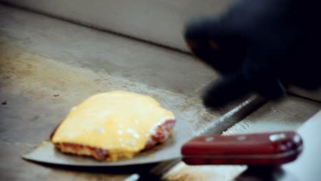 4k-kino-food-cooking-aufnahmen von einem koch, der einen köstlichen hausgemachten burger in der küche eines restaurants in slowmotion zubereitet und den käse-rind-burger vom grill entfernt