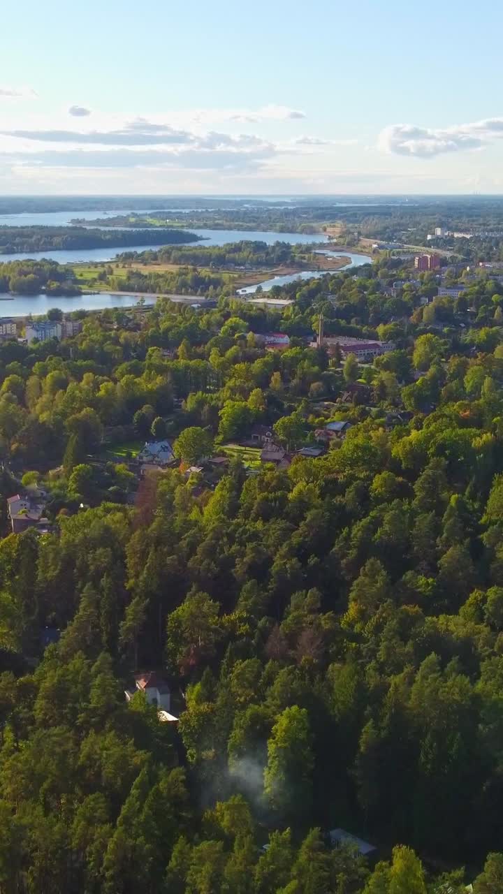Pedestal shot of a green suburban area, nearby a river, houses between trees and grassland, sunny, copy space