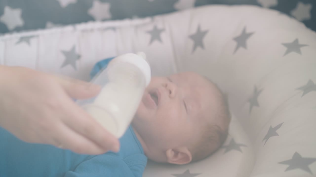 la mamma nutre il figlio con un mix di latte in un confortevole bozzolo