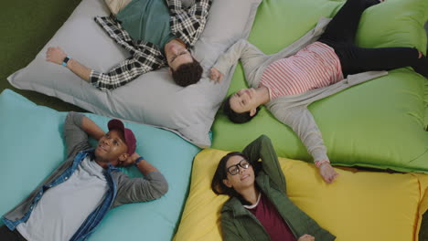 top-view-happy-group-of-business-people-jumping-on-colorful-pillows-resting-together-exhausted-after-working-relaxing-diverse-colleagues-smiling-enjoying-creative-office-workplace