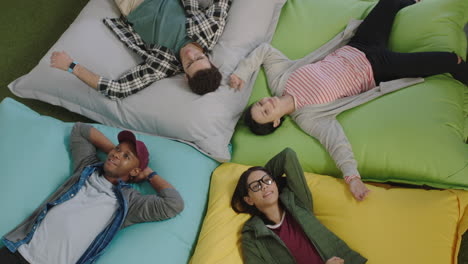 top view happy group of business people jumping on colorful pillows resting together exhausted after working relaxing diverse colleagues smiling enjoying creative office workplace