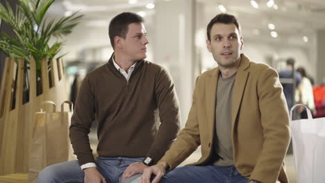 two men having a conversation and waiting in a shopping mall
