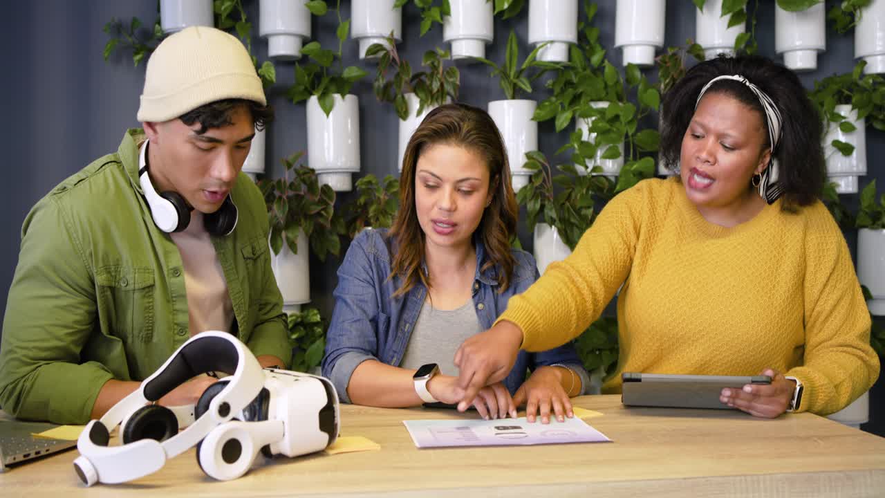 Colegas de trabalho diversos deslizando uma folha para revisão na mesa, inclinando-se, apontando e batendo para chegar a um consenso
