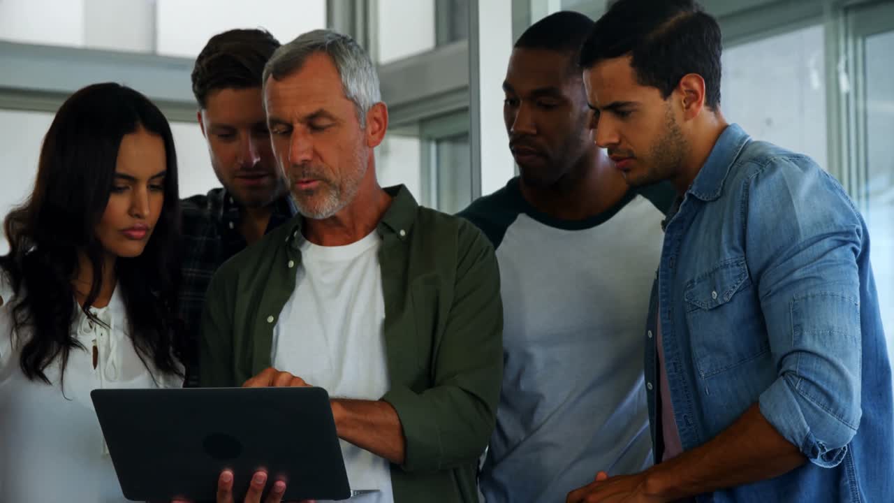 grupo de ejecutivos discutiendo sobre una computadora portátil