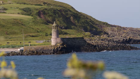 wide shot of port logan old lighthouse with foliage in foreground