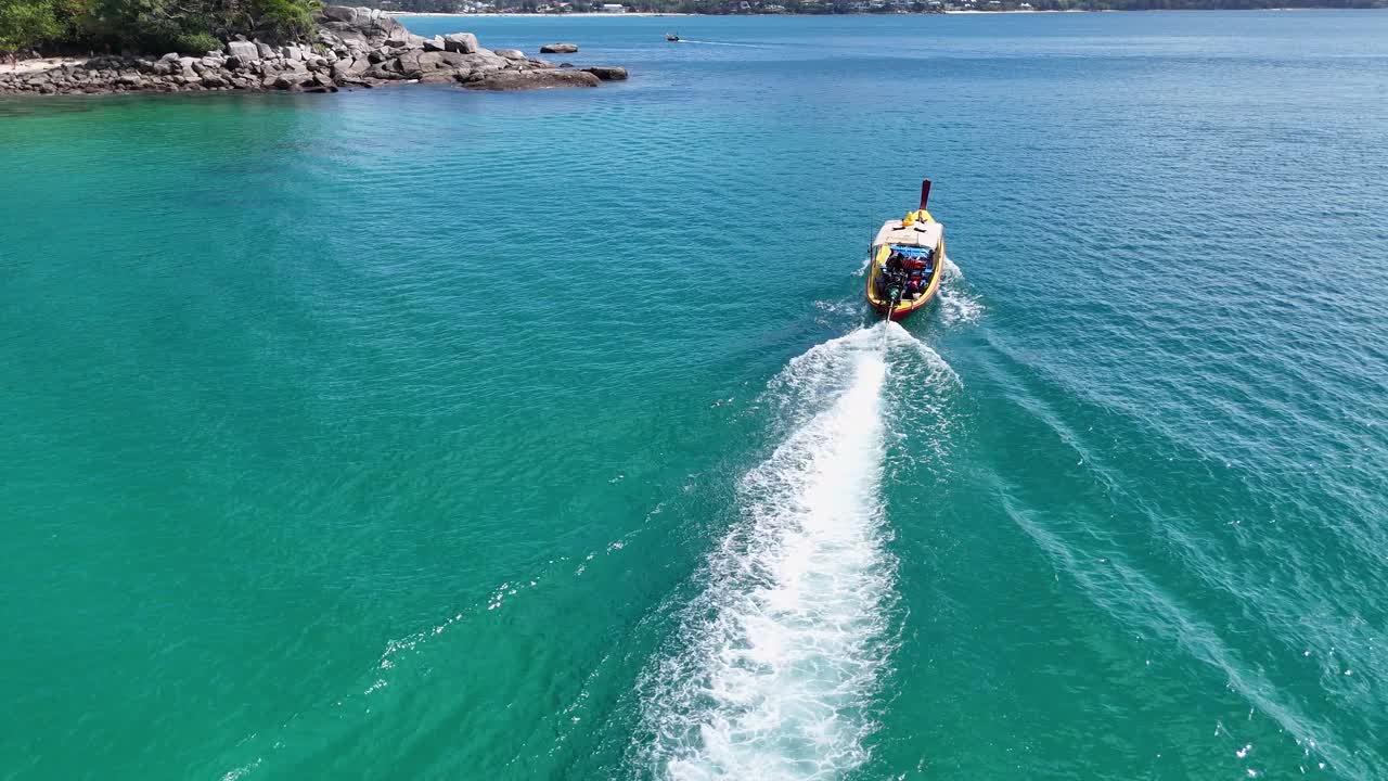 imágenes aéreas de un barco de cola larga navegando a través de aguas turquesas cerca de phuket, tailandia, mostrando paisajes vibrantes y movimiento suave