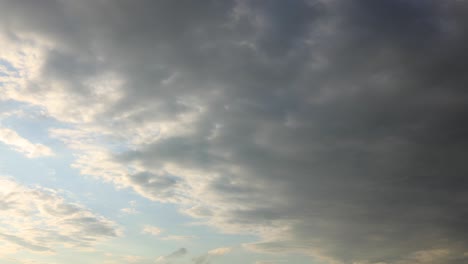 Light-rays-underneath-dramatic-slow-cumulus-cloud-formations-passing-by-slowly-into-sunset