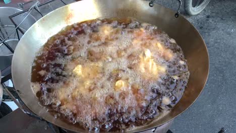 deep frying chicken in big pan on street food of thailand