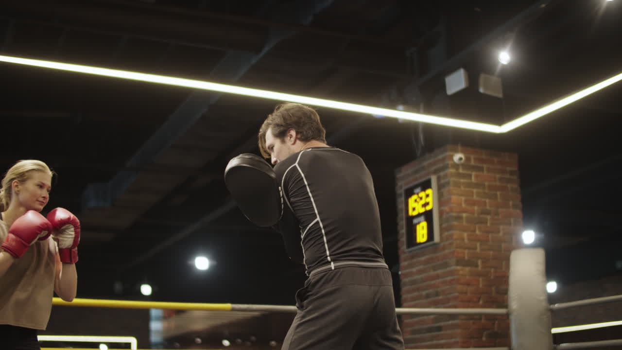 스포츠 클럽에서 다리 타격을 연습하는 활기찬 스포츠 여성. 체육관에서 권투하는 체력있는 소녀