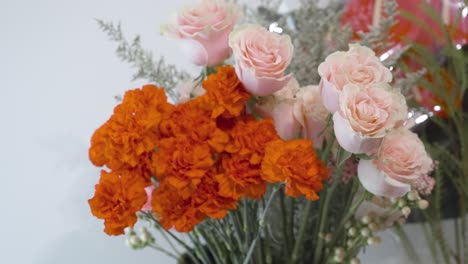 rosas en rosa claro y claveles rojos en primer plano