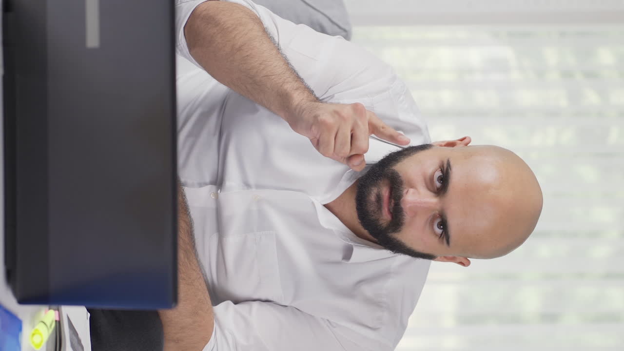 Vertical video of Home office worker man looking at camera with a stern angry warning.