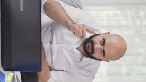 vertical video of home office worker man looking at camera with a stern angry warning.