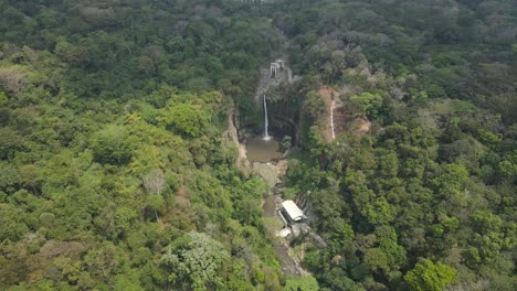 beautiful waterfall in tropical indonesian forest seen from above, with dramatic rocky canyon, dense green jungle canopy, and clear natural pool forming a scenic wild landscape