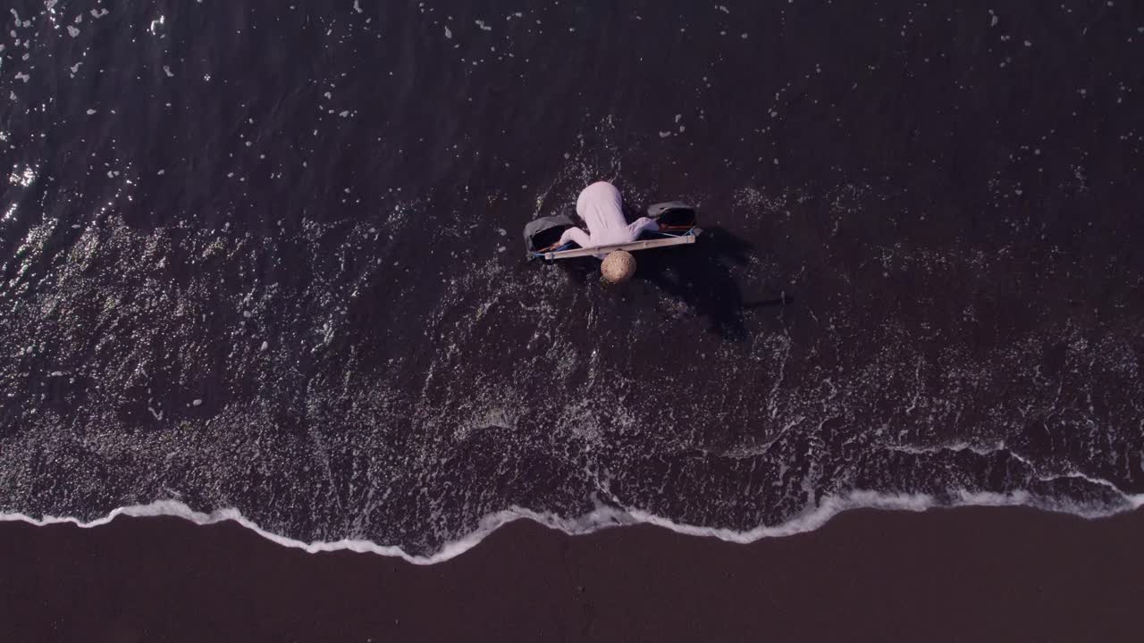 Local salt farmers on black sand beach in Klungkung, Bali