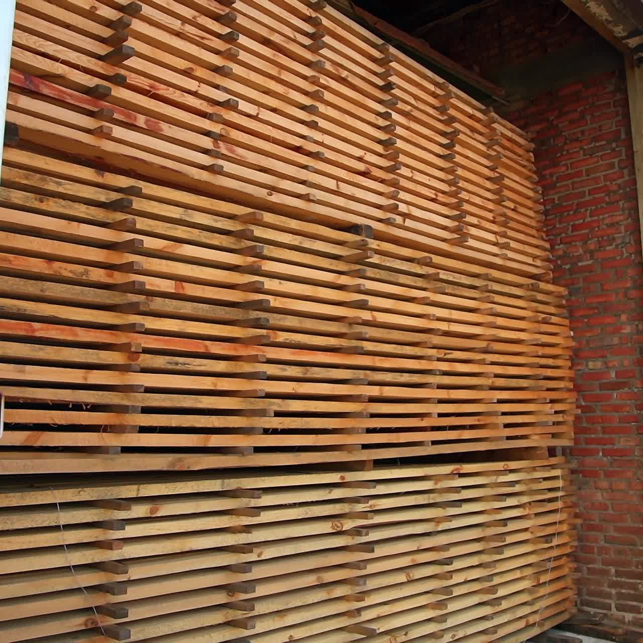 Wooden planks piled in the warehouse. Sight of an open barn filled with wood for manufacturing doors
