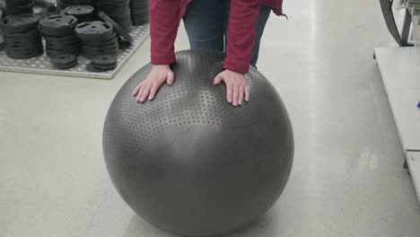 woman in store buys fitball. she touches it with her hands testing its strength