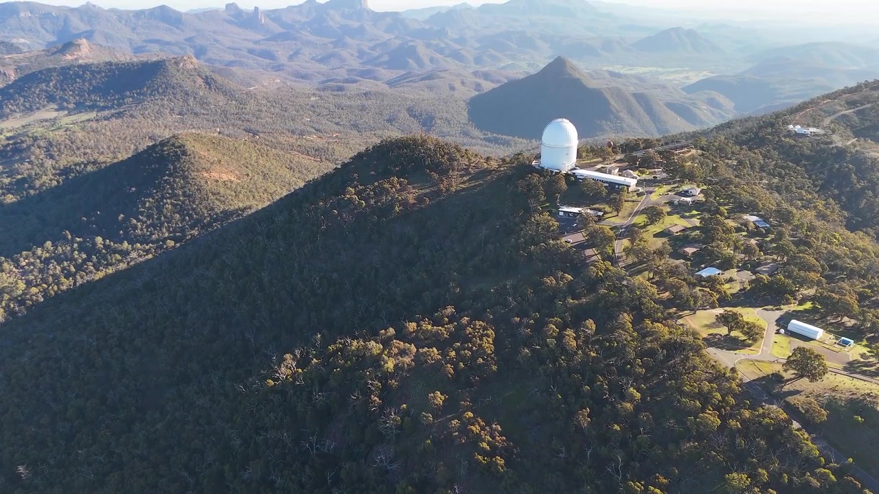 Large vue aérienne de dômes de télescopes au sommet d'une chaîne de montagnes dans le parc national de Warrumbungle, Australie.