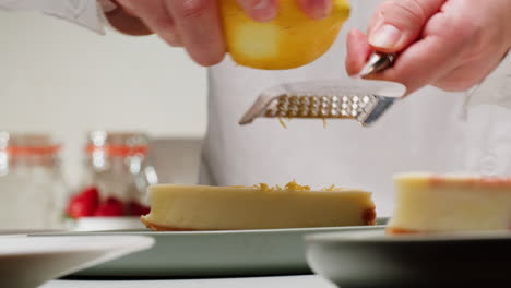 chef zesting lemon over cheesecake