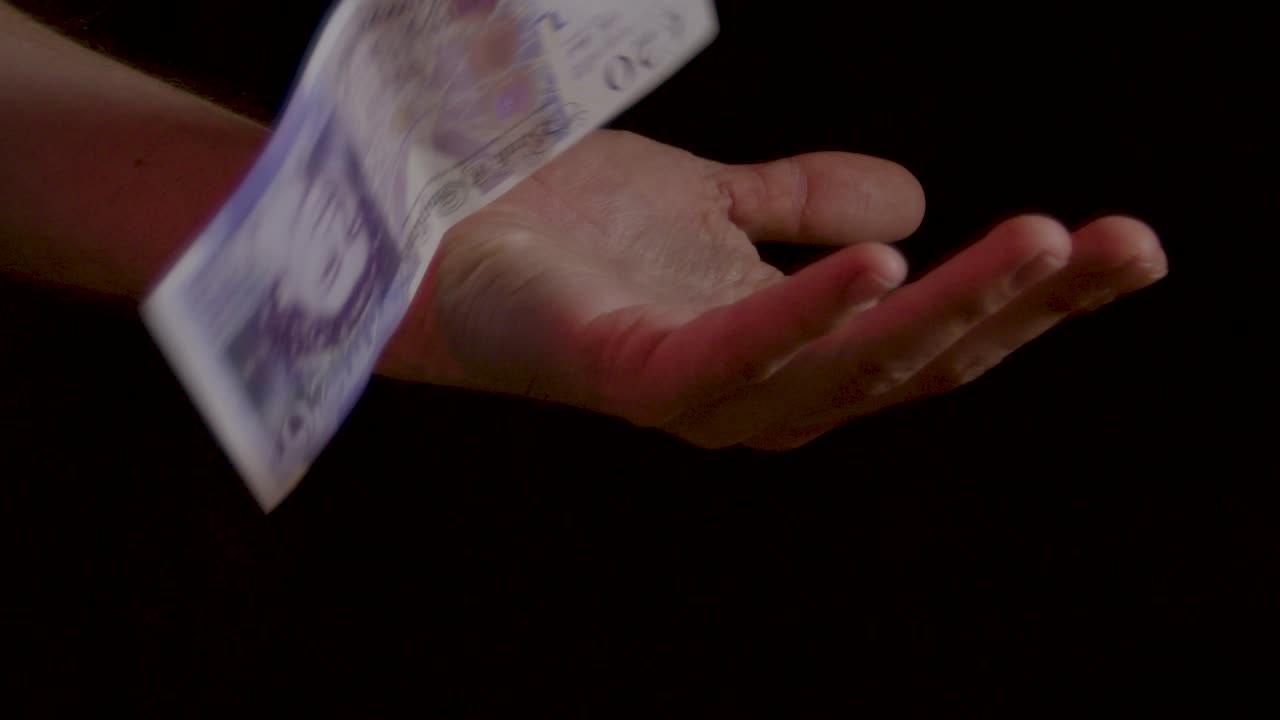 손을 통해 떨어지는 현금 돈은 슬로우 모션으로 검은 배경에 가까이