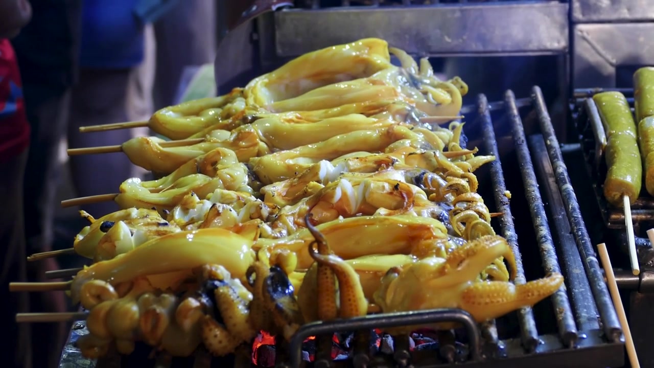 Asian Vedor Selling Grilled Squid at Night Market