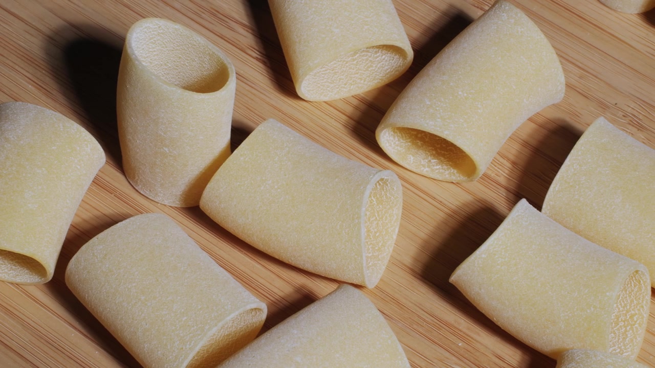 Primo piano di pasta paccheri secca su sfondo di legno