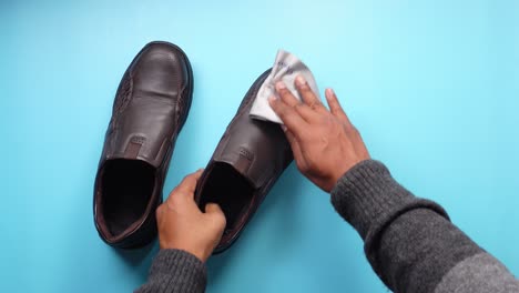 hombre limpiando zapatos de cuero marrón