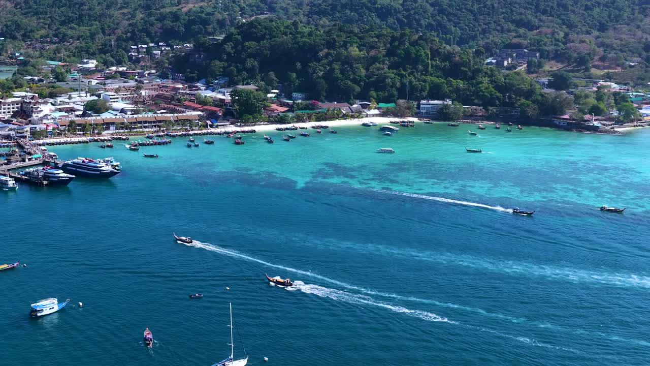 Inquadratura aerea ad angolo elevato di una baia tropicale con barche che si muovono attraverso l'acqua turchese cristallina