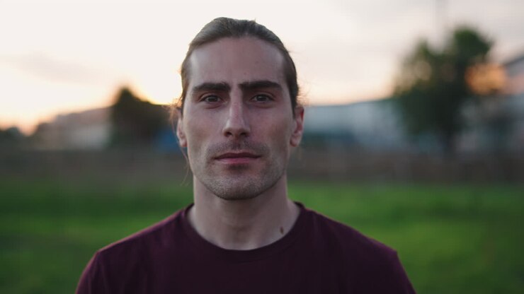 Young Man Looking at Camera Outdoors at Sunset
