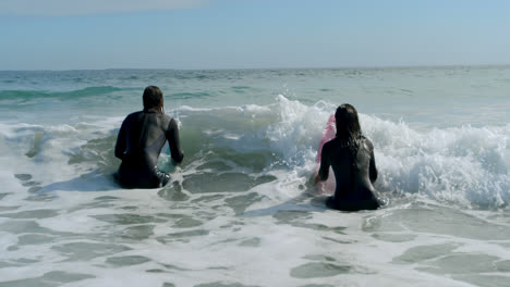 Surfer-couple-preparing-to-surf-on-the-wave-4k