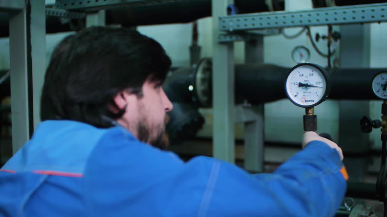 산업 시설에서 압력 측정기를 확인하는 기술자