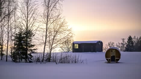 Lapso-De-Tiempo-De-Estrellas-Voladoras-Durante-La-Puesta-De-Sol-En-El-Cielo-En-Un-Paisaje-Invernal-Blanco-Con-Sauna-De-Barril-Y-Cabaña-De-Madera