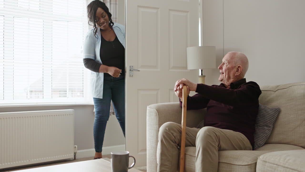 Elderly man sitting at home with nurse visiting