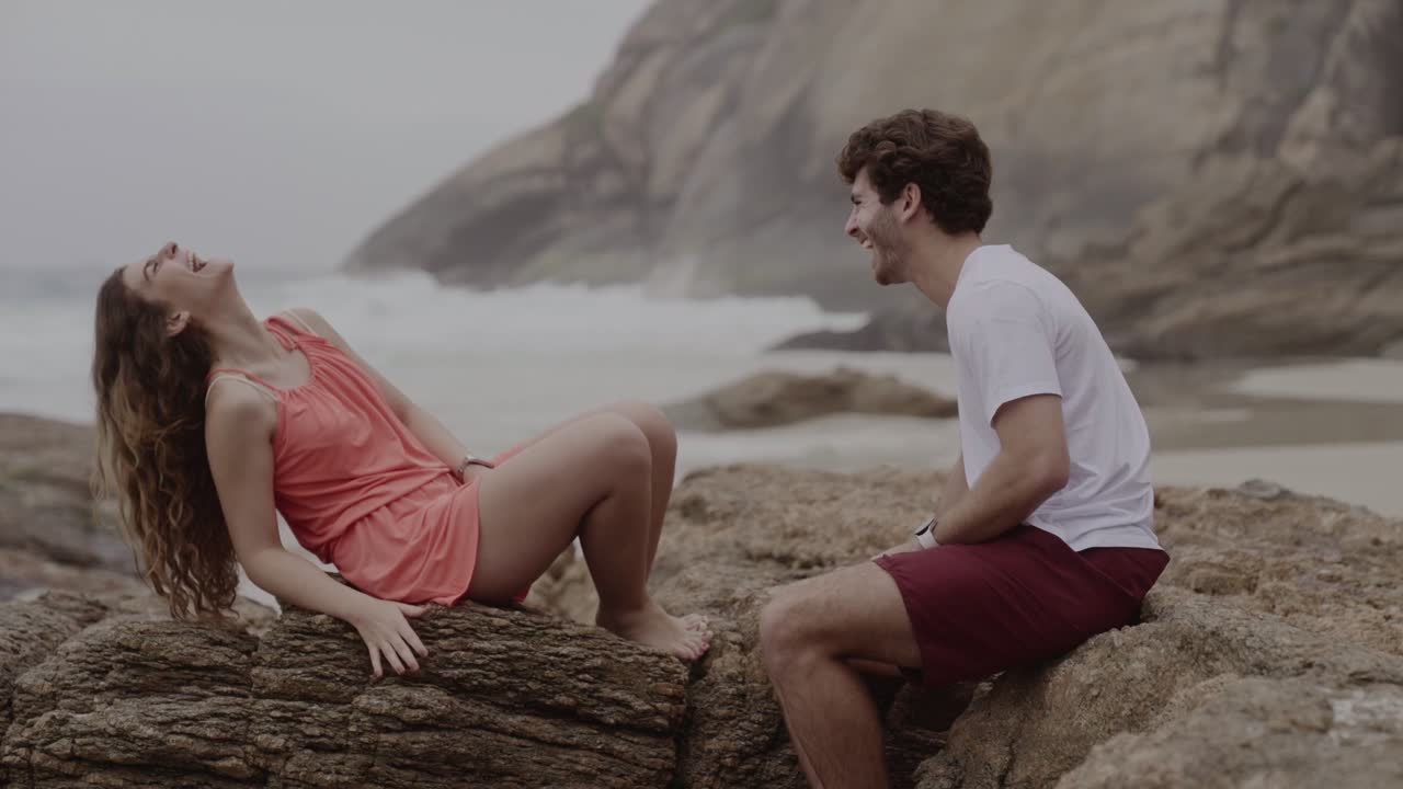 A happy couple laughing on the rocks at the beach