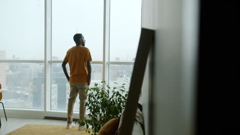 man looking out a high-rise window