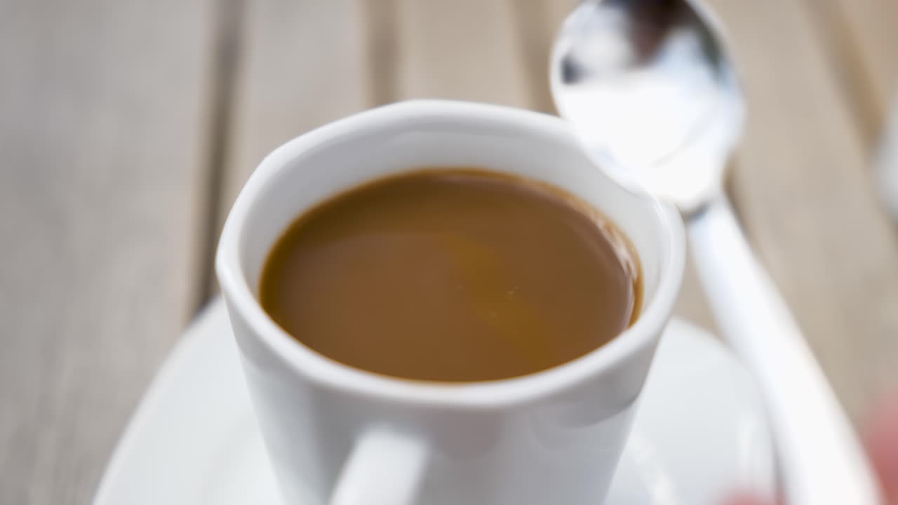 añadiendo una cucharada de azúcar en un café con nata