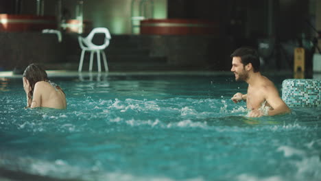 Pareja-Feliz-Chapoteando-Juntos-En-La-Piscina.-Pareja-Romántica-Divirtiéndose-En-La-Piscina