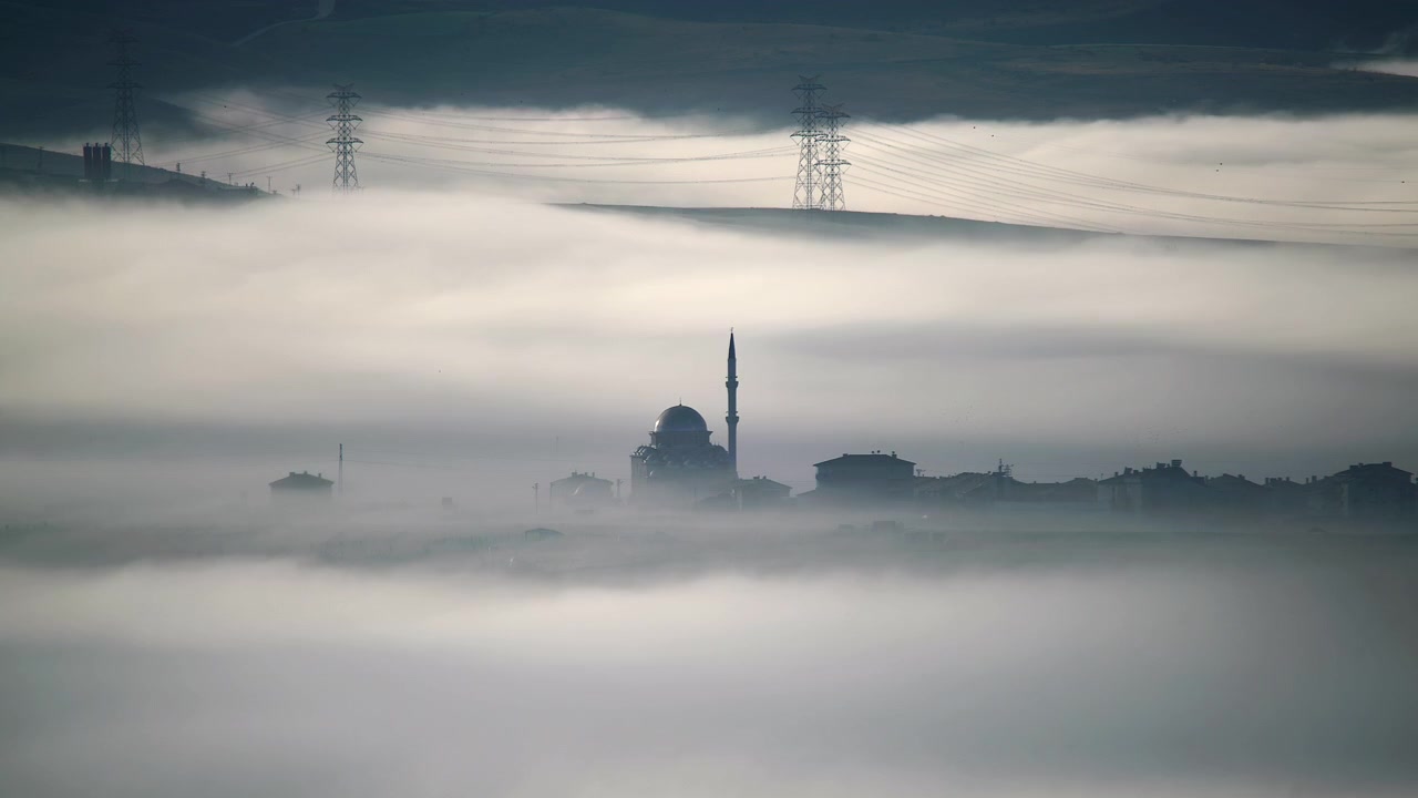 Mosque Silhouette Emerging from Thick Morning Fog in Rural Landscape