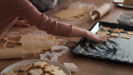 caucasian girl cutting out homemade cookies with grandmother