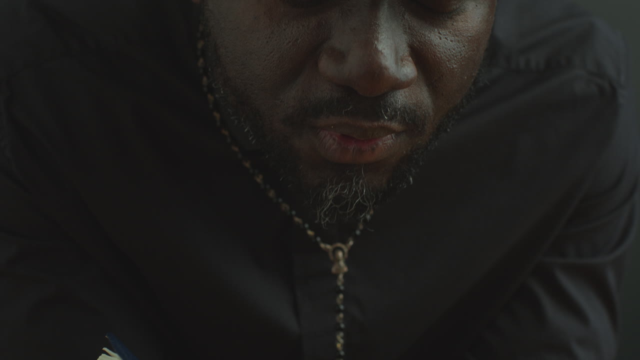 Black Catholic Priest Holding Holy Bible and Saying a Prayer